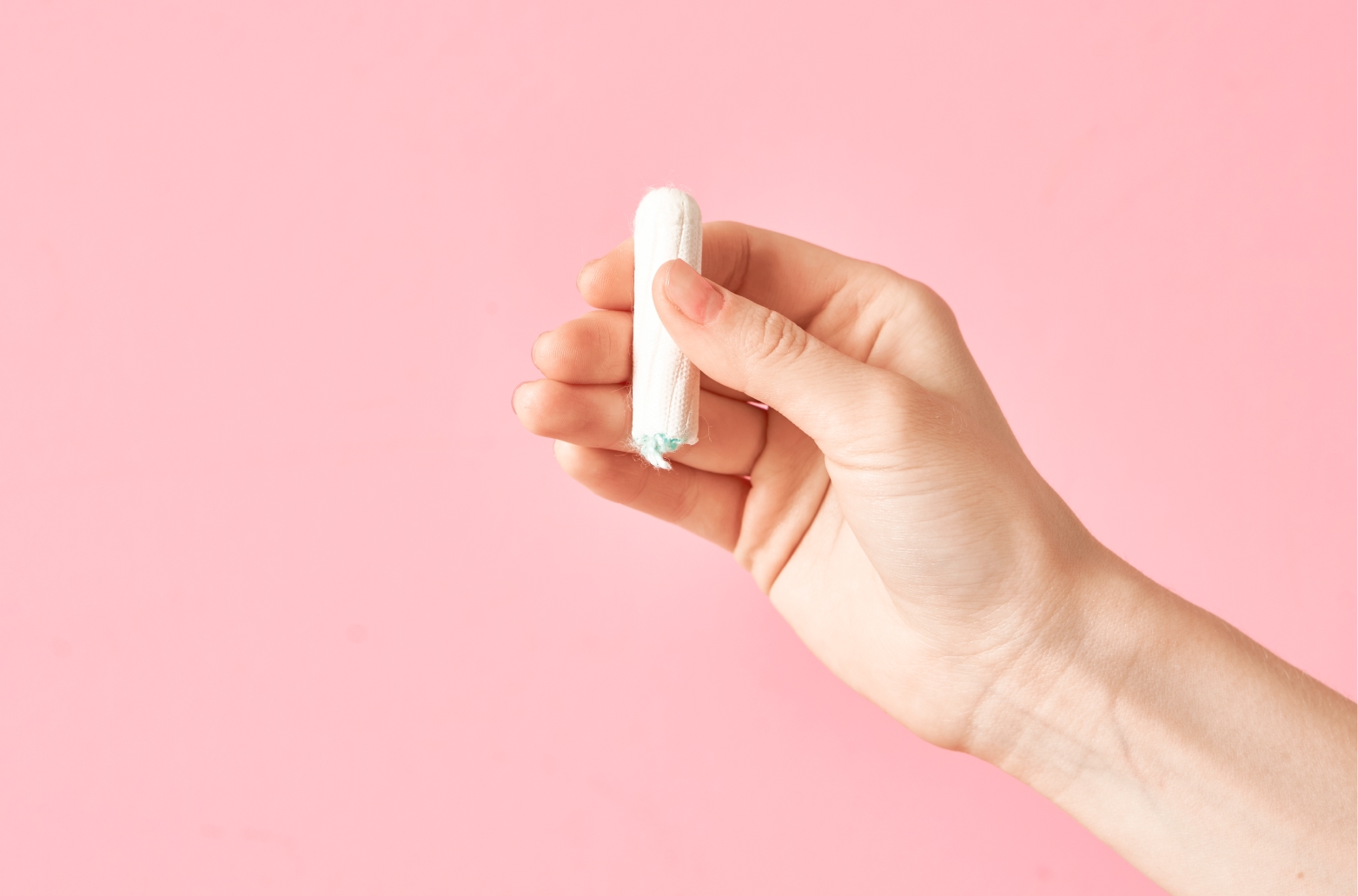 Женская рука держит обычный тампон. Почему возникает аллергия на тампоны и как выбрать безопасный вариант